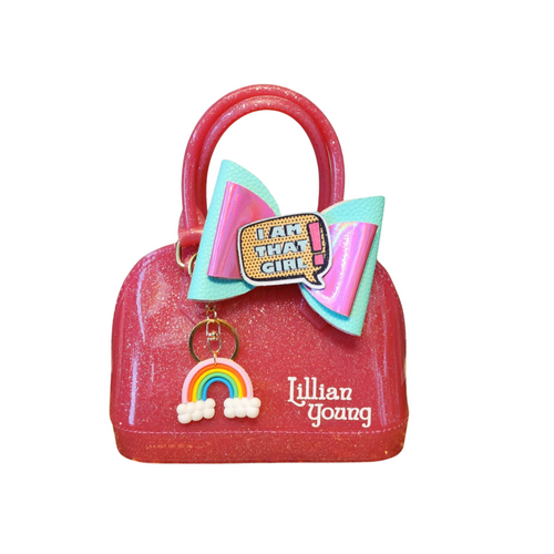 Hot pink glittery handbag with a large bow and rainbow charm on a white background